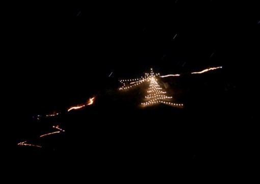 Una suggestiva immagine della fiaccolata in Manavello dello scorso anno e dell'accensione dell'laberro di Natale e della cometa (foto Celestino Panizza).